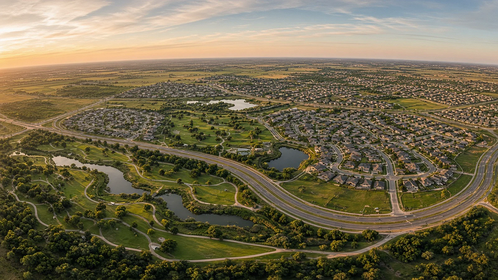 Wide curved aerial panorama over a master-planned community and park in North Texas at golden hour