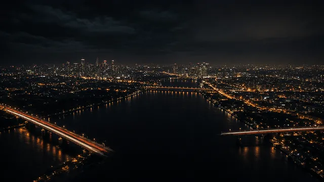 A night aerial view of a city skyline and river, with light trails on the bridges