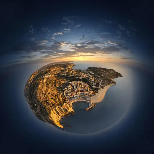 A coastal town and cliffs rendered as a spherical 360-degree aerial panorama at golden hour